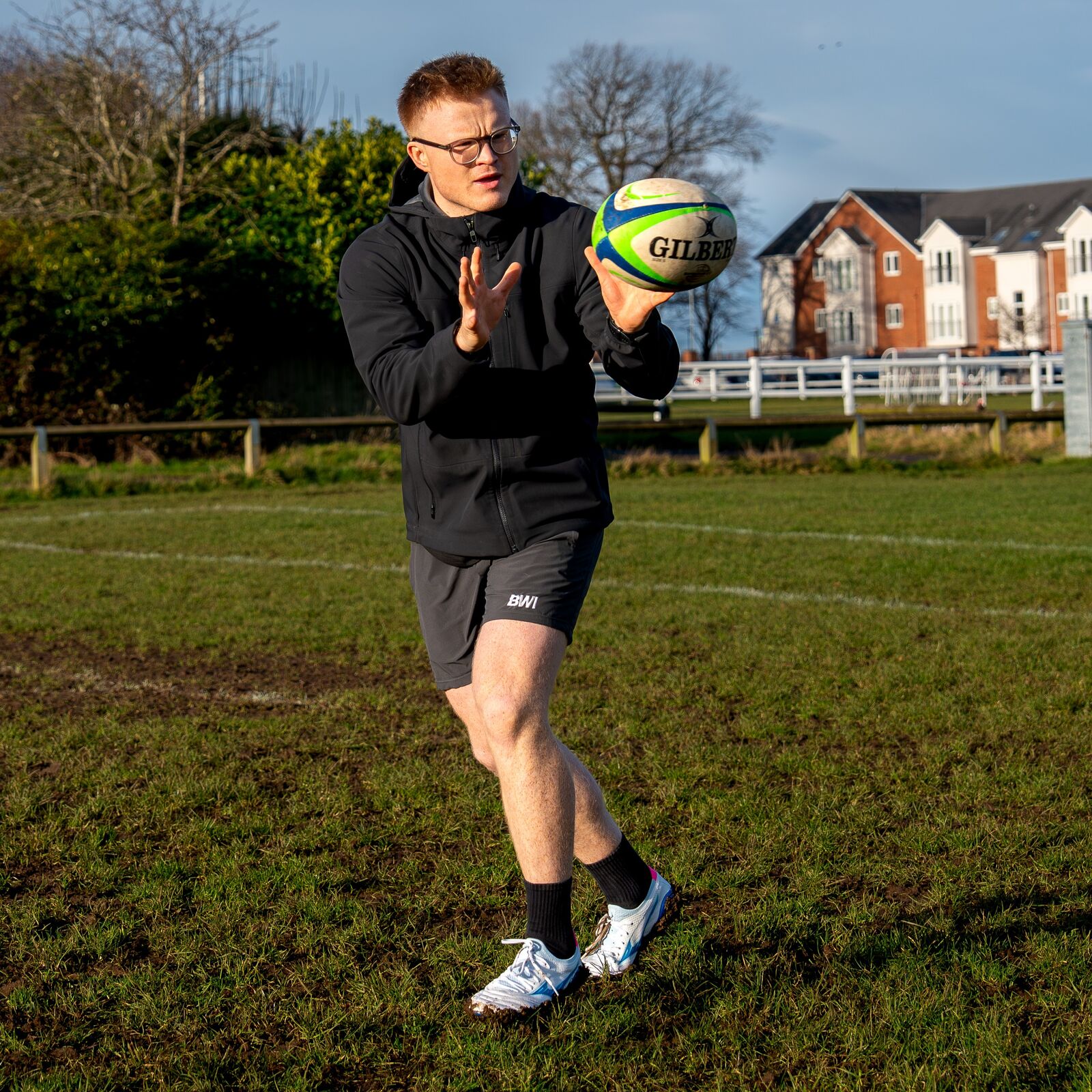 Ed Irons, founder of Built With Irons, catching a rugby ball on the pitch